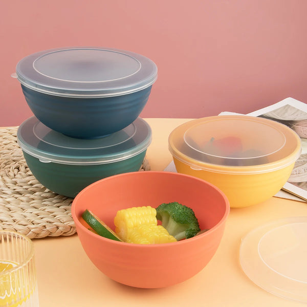 A stack of reusable food storage bowls in teal and orange, with a single orange bowl filled with green and yellow vegetables.