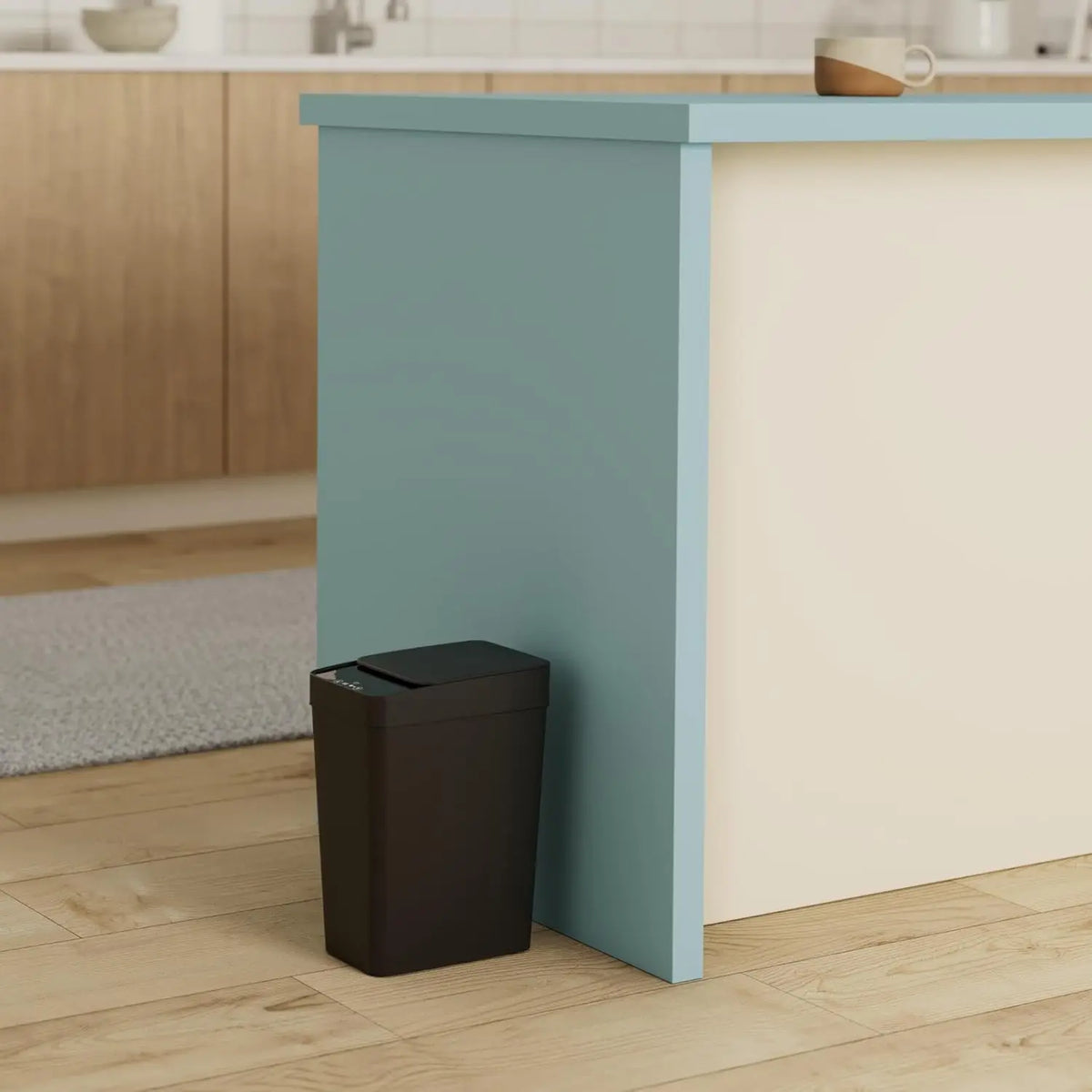 A modern light blue kitchen island with a cream countertop and a dark trash can placed in front of it.