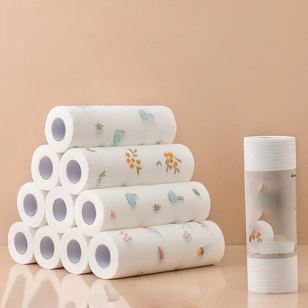 A stack of white reusable non-woven kitchen dish cloths rolled up on a light beige surface.