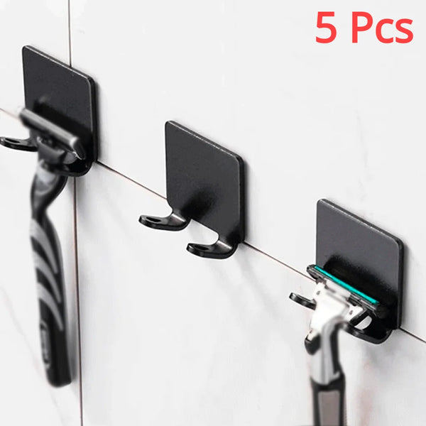 Five black aluminum shaving razor storage racks mounted on a white tile wall.