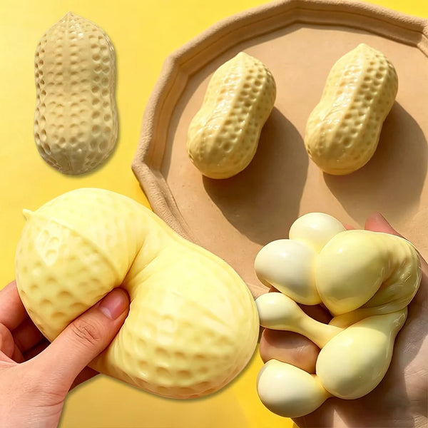 A hand holds a yellow peanut squishy stress relief toy resting on a light brown tray.