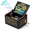 A vintage engraved wooden music box with a lid open, featuring a sunflower design and musical notes.