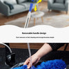 A hand is using a blue, fluffy duster to clean a surface.