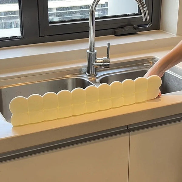 A silicone sink splash guard and water blocking strip is placed across a kitchen sink basin.