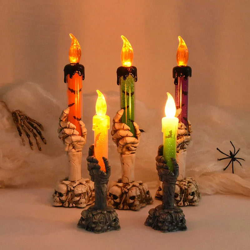 Three skeleton hand candle holders with glowing orange, green, and purple LED candles.