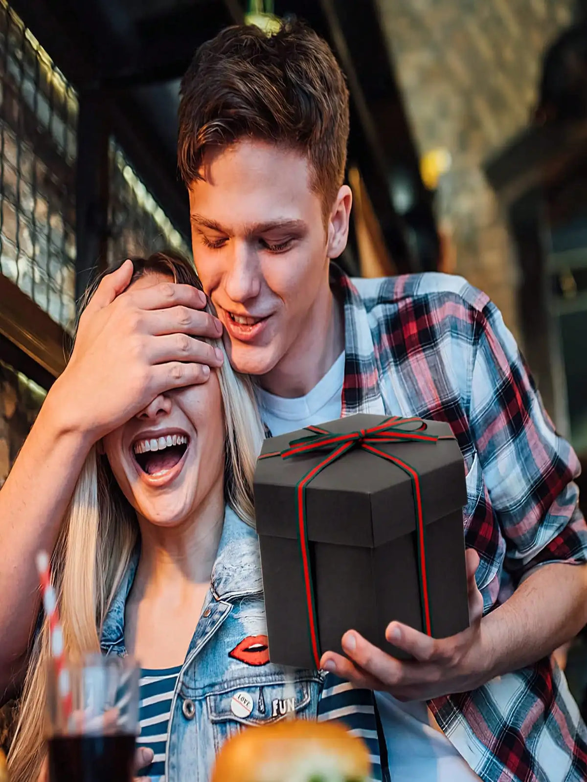 Ein junger Mann lächelt, während er eine schwarze Geschenkbox für ein DIY-Fotoalbum hält.
