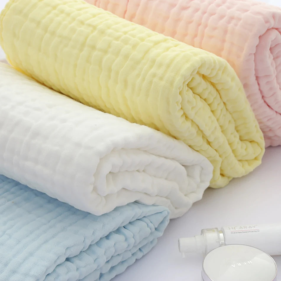 Una pila de cinco toallitas húmedas orgánicas de algodón para bebé y cara en varios colores, incluyendo amarillo, rosa, blanc