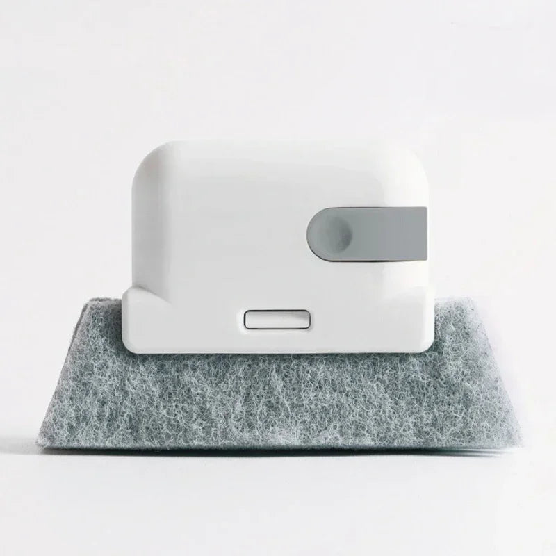 A white cleaning brush with a gray section rests on a gray, textured mat.