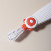 A white silicone baby bottle cleaning brush with an orange grip and bristles is shown against a light background.