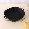 Black reusable silicone air fryer liner with fluted edges shown on a light surface.