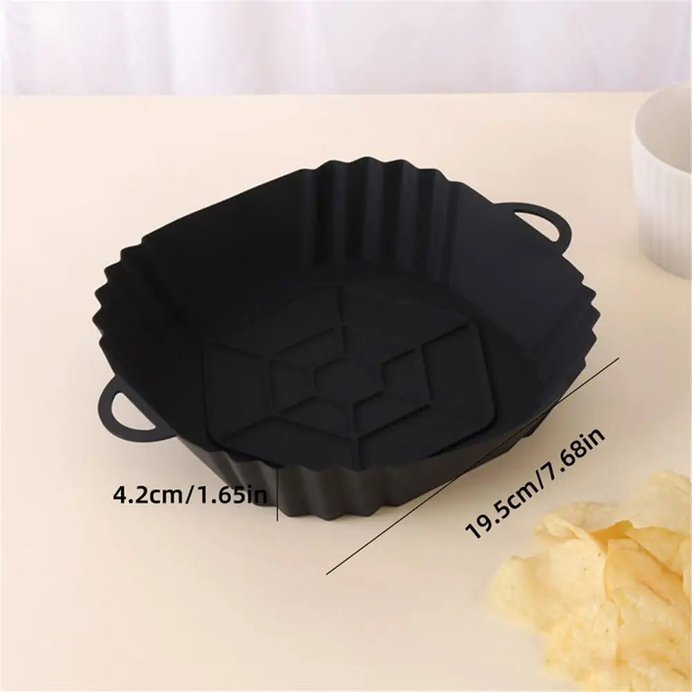 Black reusable silicone air fryer liner with fluted edges shown on a light surface.