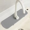 Eine weiße Silikon-Spülmitt-Ablaufmatte mit einem gebogenen Wasserhahn ist in einer weißen Küchen- oder Badspüle installiert.