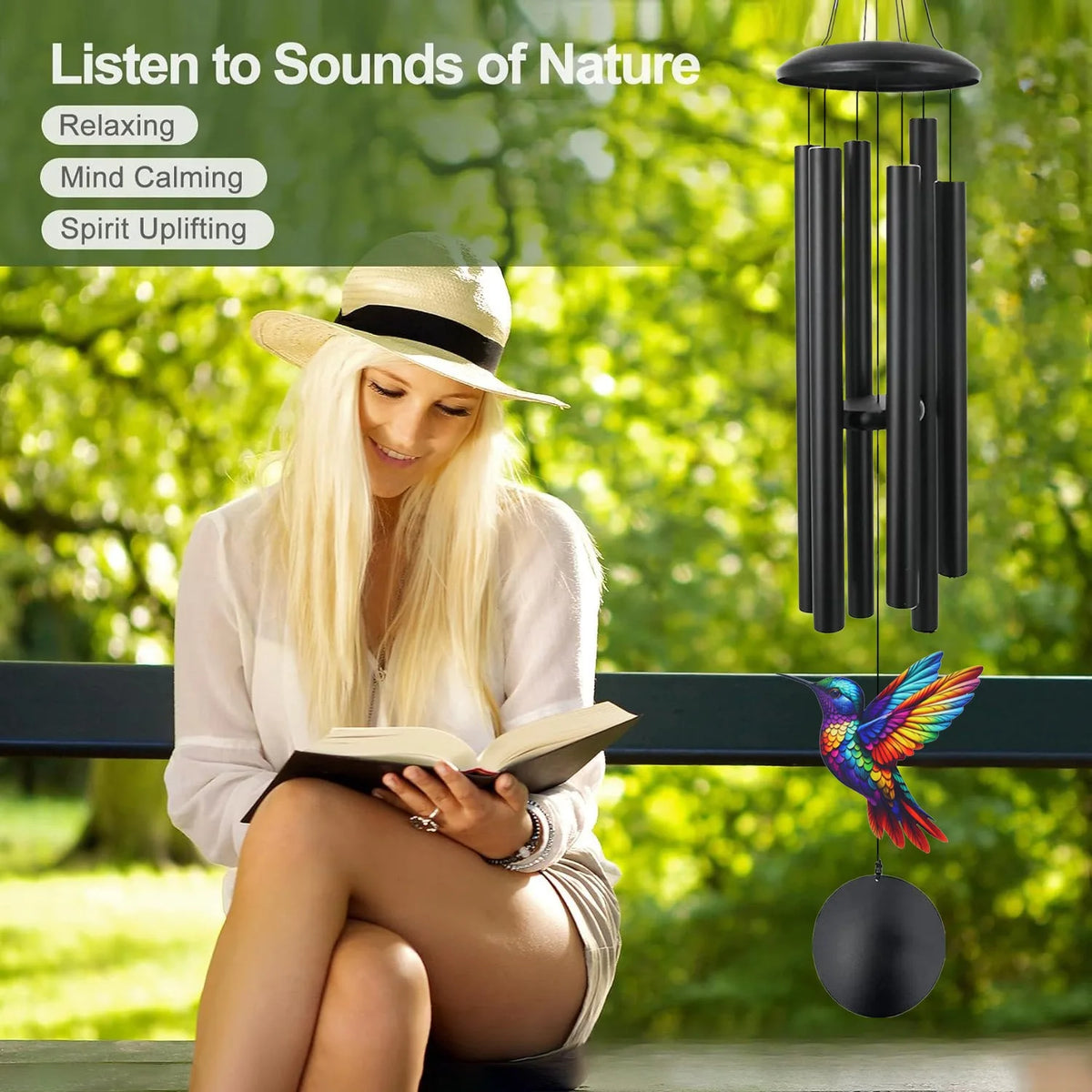 A blonde woman reads a book outdoors while a hanging metal wind chime decoration is visible in the background.