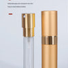 A clear glass perfume spray bottle with a gold-colored dispenser and a matching gold cylindrical container.