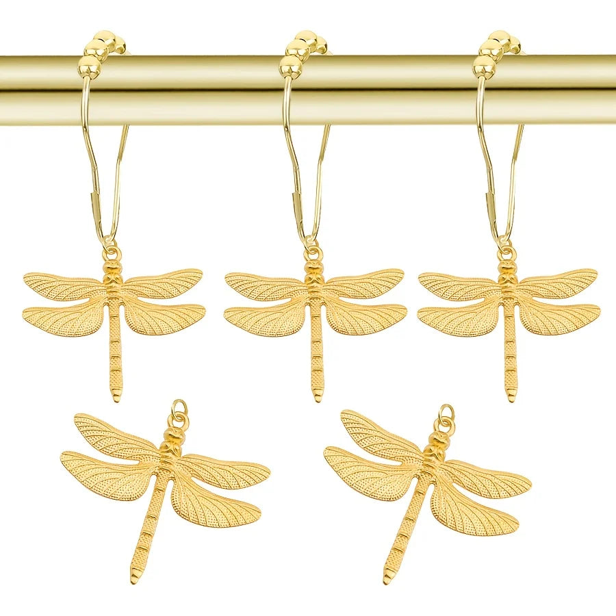A set of gold-toned dragonfly shower curtain hooks hanging from a brass rod.