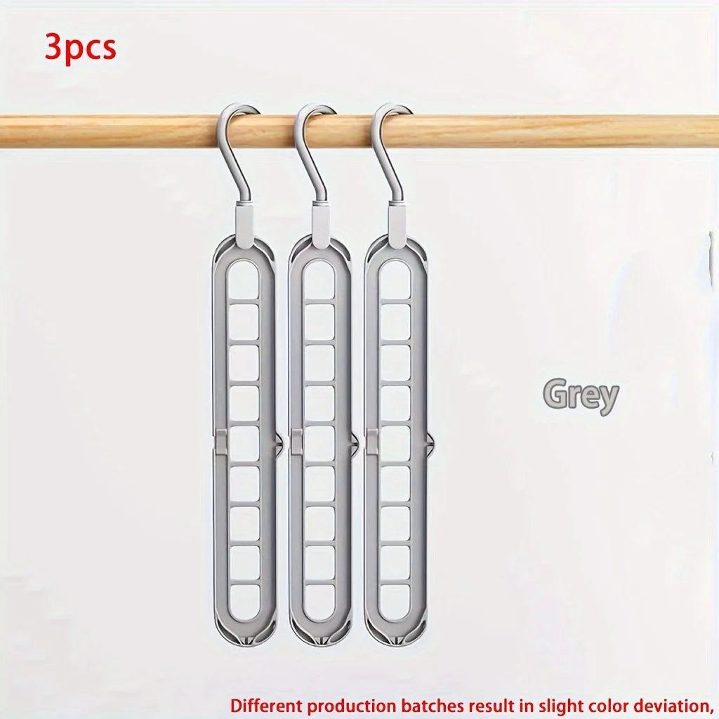 Three grey foldable plastic hangers hanging from a wooden rod.