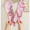 Une paire de tongs pliables roses en EVA tenues par des mains sur un fond clair.