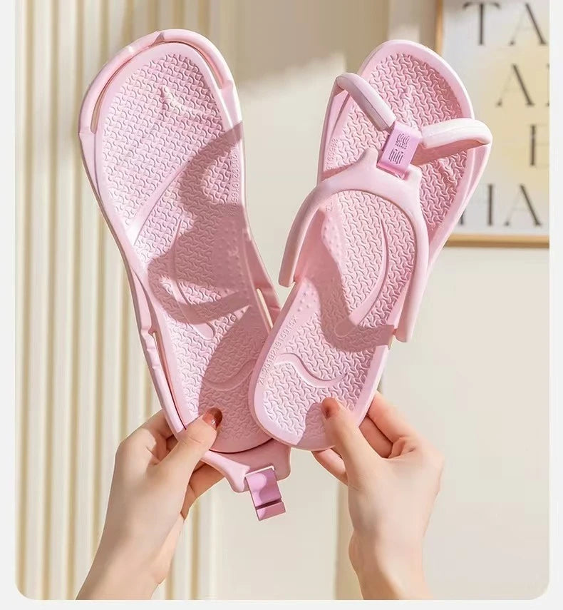 Une paire de tongs pliables roses en EVA tenues par des mains sur un fond clair.