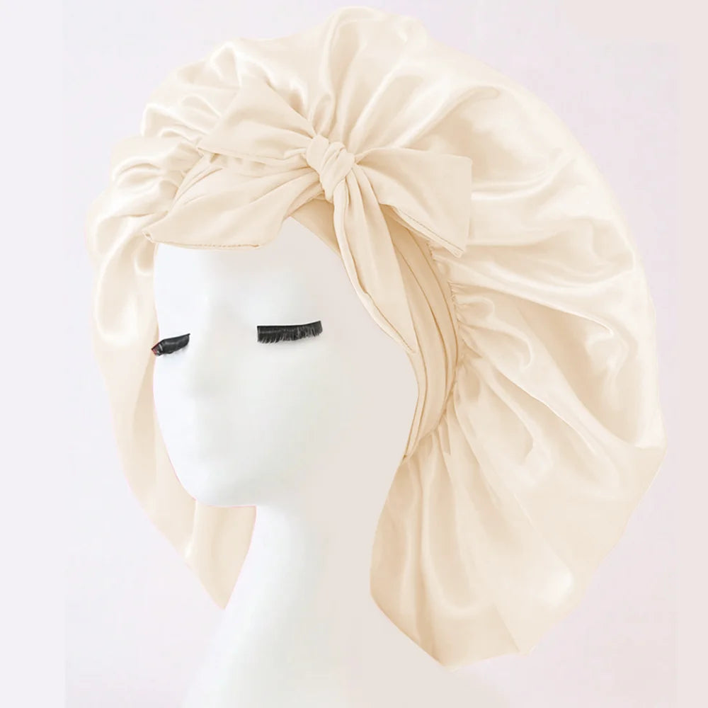 Heller beiger Seiden-Haarbonnet mit großer Schleife, präsentiert auf einem weißen Mannequin-Kopf.