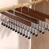 Nahaufnahme von Holzkleiderbügeln mit silbernen Clips, die an einem goldfarbenen Stab hängen.
