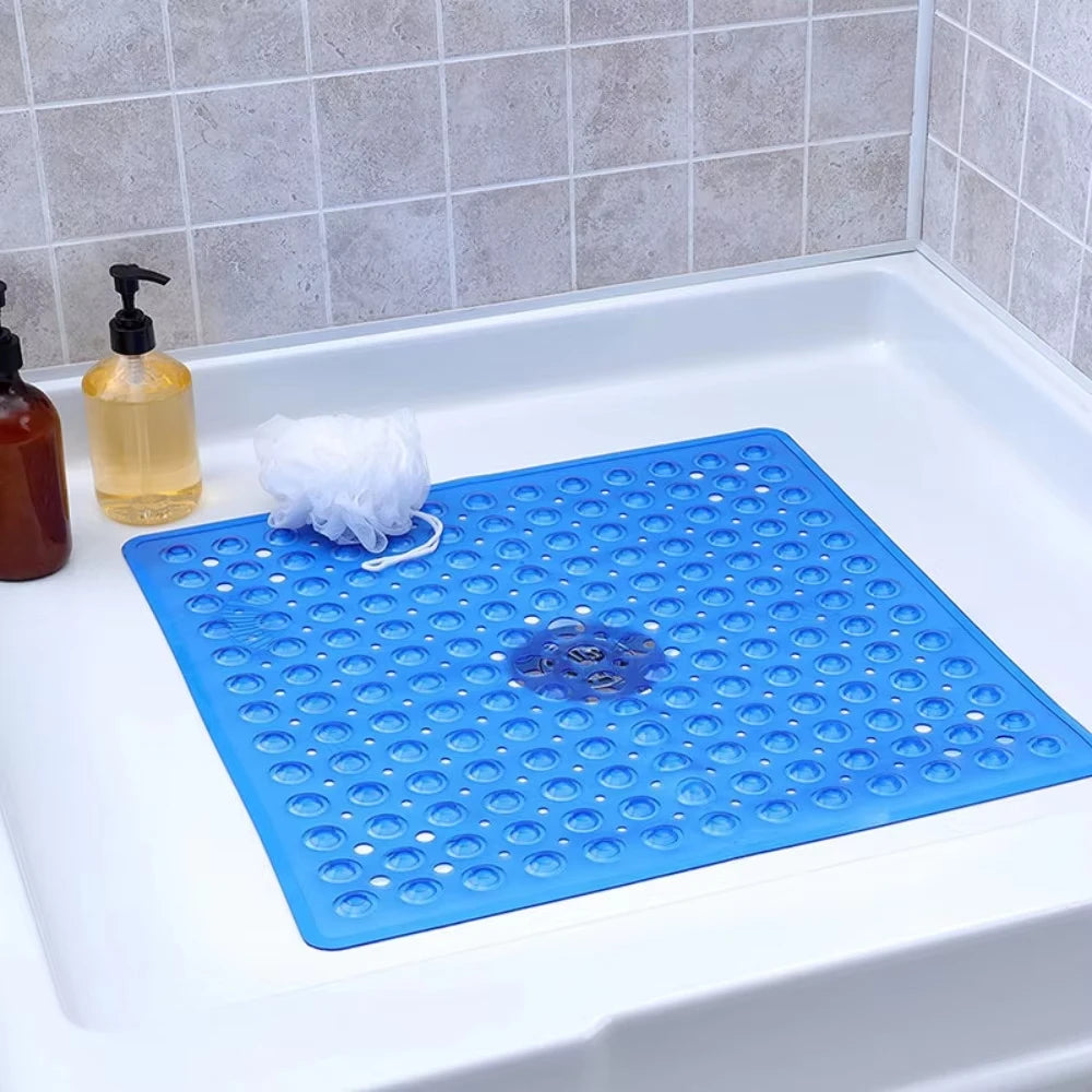 A blue non-slip shower mat with suction cups is placed in a white bathtub.