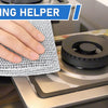 A hand is cleaning a stovetop with a non-scratch steel wool dishcloth.