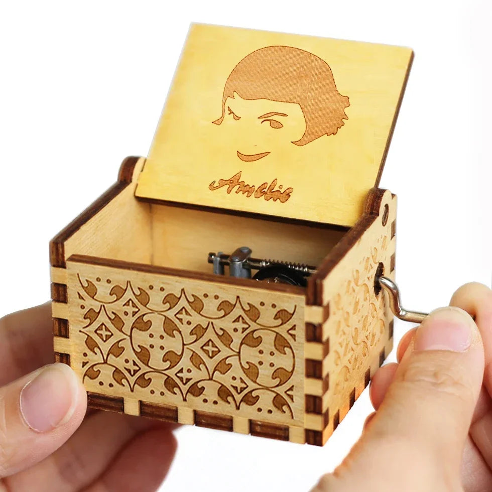 An antique wooden hand crank music box with a light wood casing and a carved face on the lid.