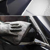 A black microfiber towel is shown cleaning a car's exterior surface.