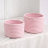 A pink handwoven cotton rope storage basket sitting on a white surface.