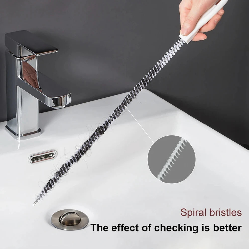 A hand is using a flexible drain cleaning brush with spiral bristles to clean a kitchen sink.