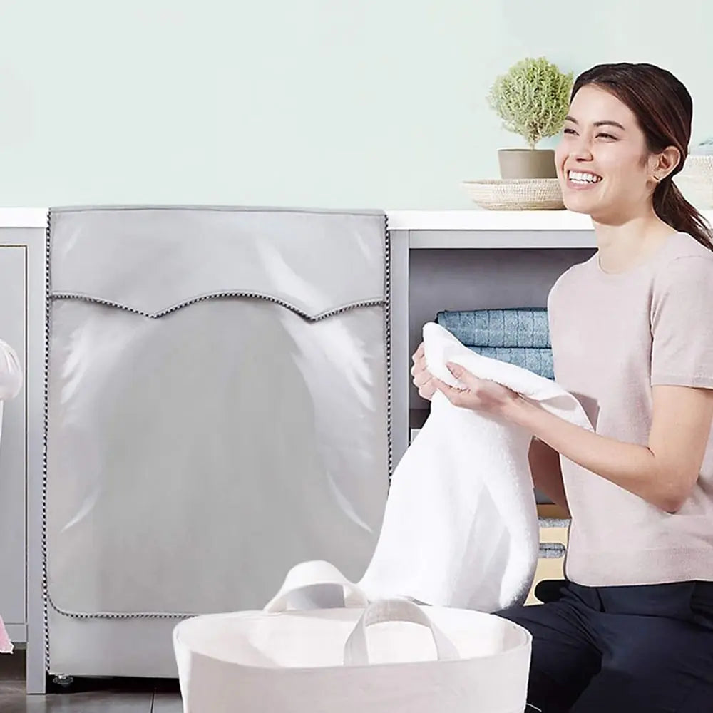 A woman is holding a white towel while sitting next to a silver Oxford washing machine cover.