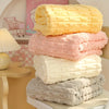 Stack of fluffy bath towels in pink, cream, and gray colors