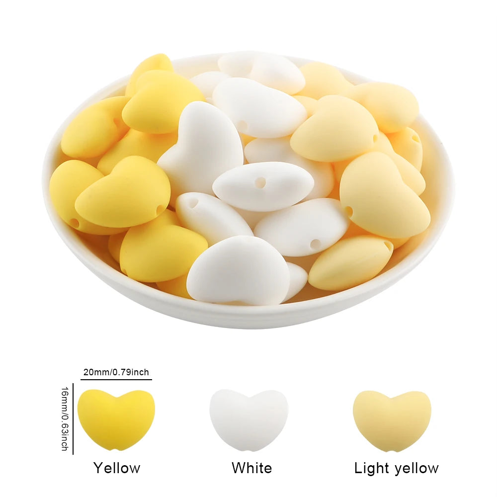 A bowl filled with 10 silicone charm beads in yellow, white, and light yellow colors.