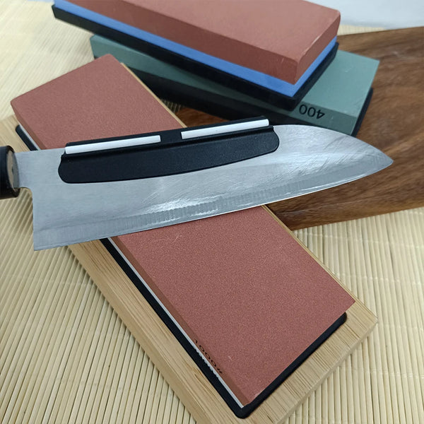 A multi-grit knife sharpening stone set with a silver blade resting on a wooden surface.
