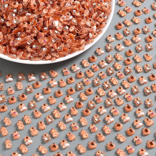 Gros plan de petites figurines de capybaras en résine brun-rougeâtre éparpillées sur une assiette blanche.