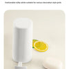 A white portable soap bar grinder with a wall-mount design is shown next to a slice of lemon.