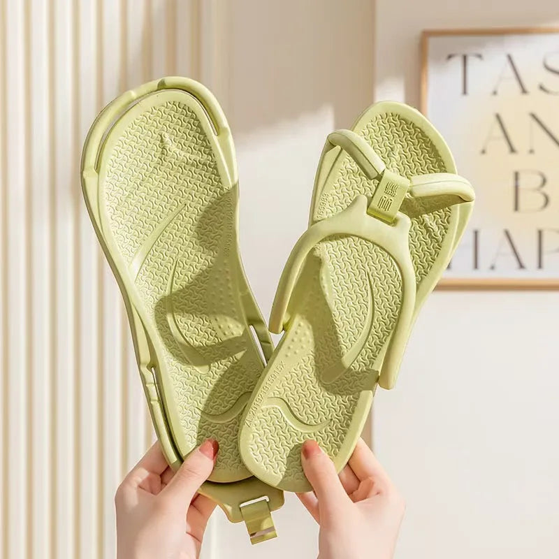 Une paire de tongs pliables en EVA vert clair, tenues par des mains sur un fond clair.