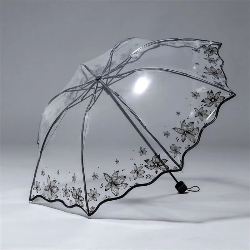 A clear, retro transparent folding umbrella decorated with black floral patterns.
