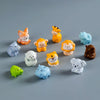 A collection of colorful mini resin cartoon animal figurines arranged on a gray surface.