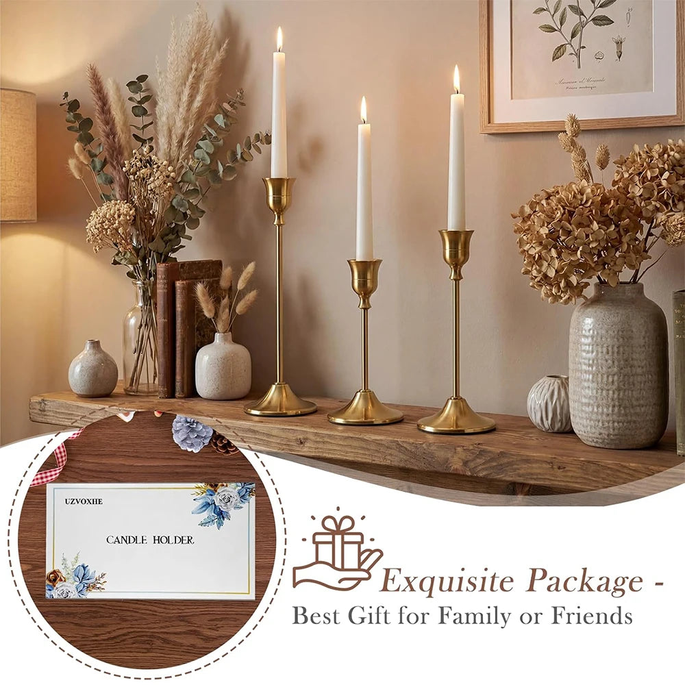 A set of six gold weighted metal taper candlestick holders displayed on a wooden surface with dried floral arrangements.
