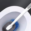 A white toilet brush with an extended handle is shown inside a toilet bowl.
