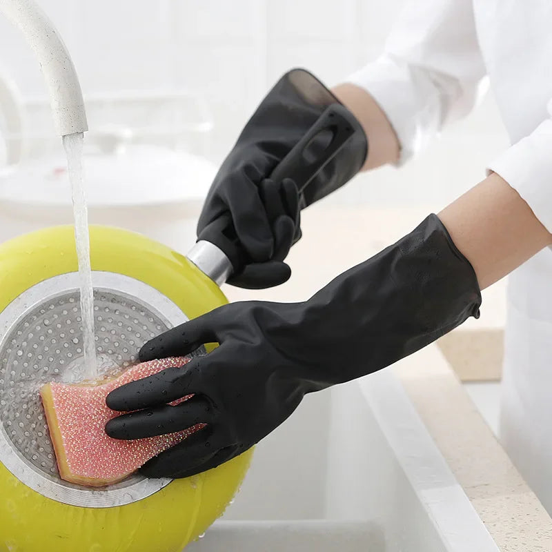 A person wearing black rubber cleaning gloves is washing a pink dish in a yellow basin.