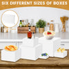 Six different sizes of white acrylic boxes stacked on a wooden table for food display
