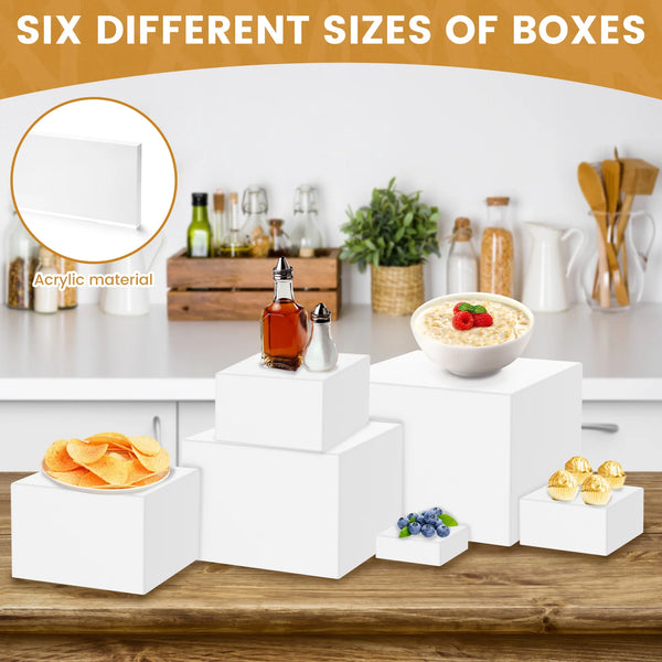 Six different sizes of white acrylic boxes stacked on a wooden table for food display