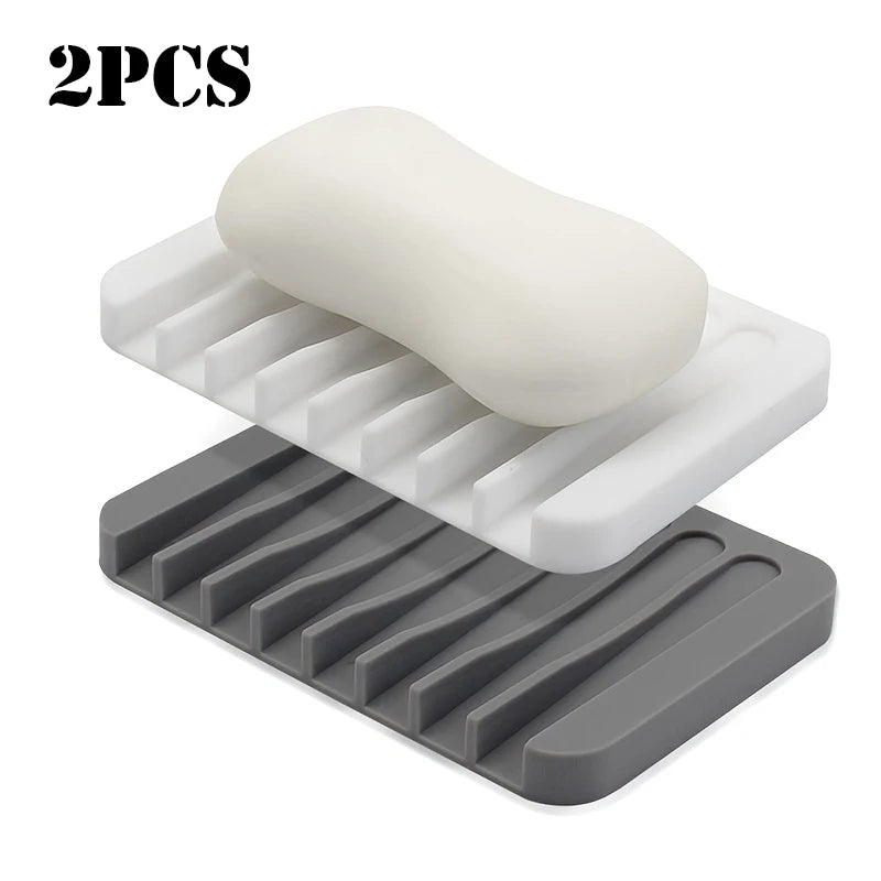 Two silicone soap dishes, one white and one gray, showing a self-draining design.