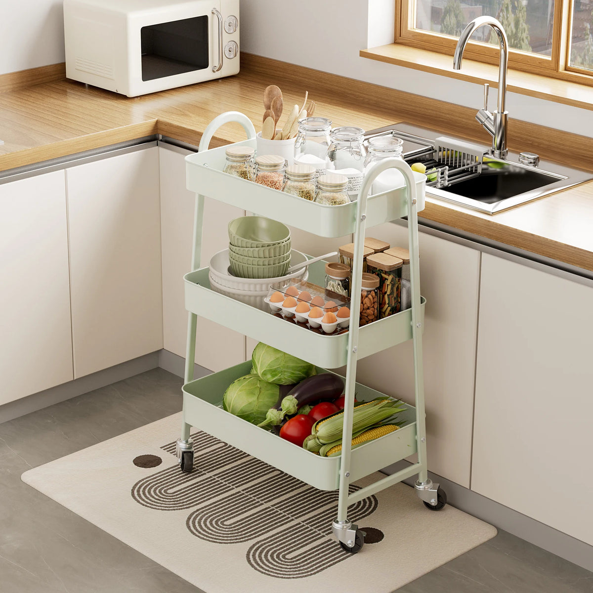 A white 3-tier metal rolling storage cart filled with fresh vegetables and kitchen items on a countertop.