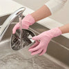 A hand wearing a pink disposable nitrile glove is using a faucet to rinse a stainless steel bowl in a kitchen sink.