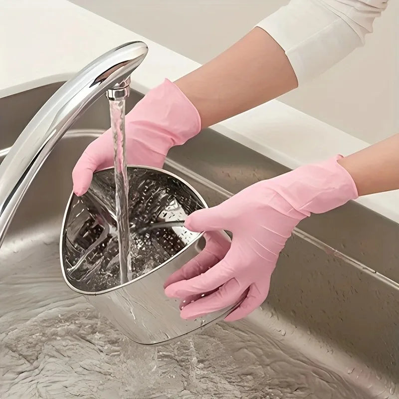 A hand wearing a pink disposable nitrile glove is using a faucet to rinse a stainless steel bowl in a kitchen sink.