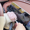 A close-up view of a pink extendable microfiber duster brush being used on the interior of a car