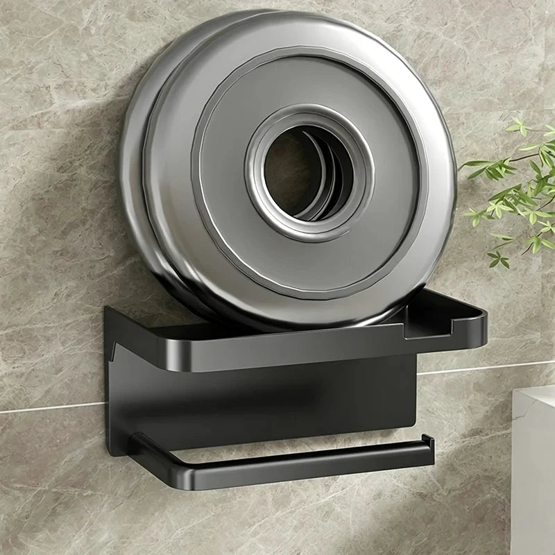 A black no-drill toilet paper holder with a storage shelf mounted on a gray tiled wall.